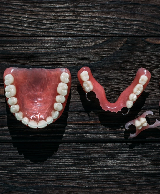 Upper and lower partial dentures placed on a dark wooden surface