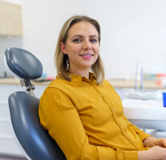 Smiling female patient sitting comfortably in dental chair during dental visit