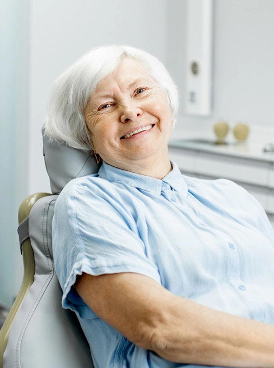 Smiling senior female patient relaxing in dental chair after root canal therapy