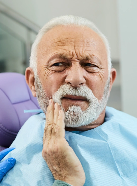 Senior male patient pointing to painful tooth indicating need for tooth extraction